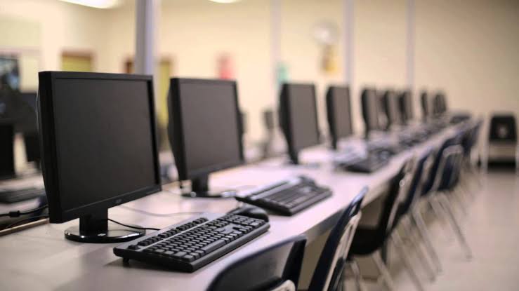 Une rangée d'ordinateurs installés le long d'une paillasse de salle de classe